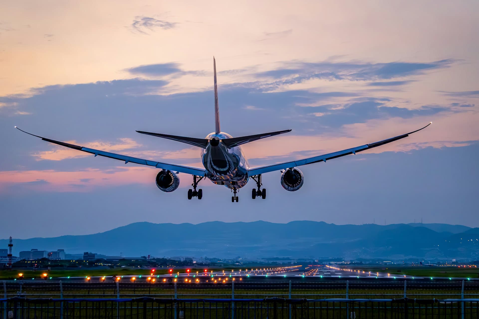 Un avion de ligne, train sorti, se pose au crépuscule au-dessus des feux de la piste